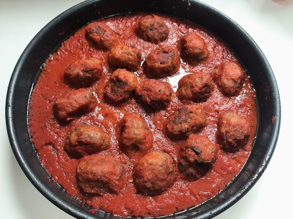 Meatballs baked in a round pan of rich tomato sauce