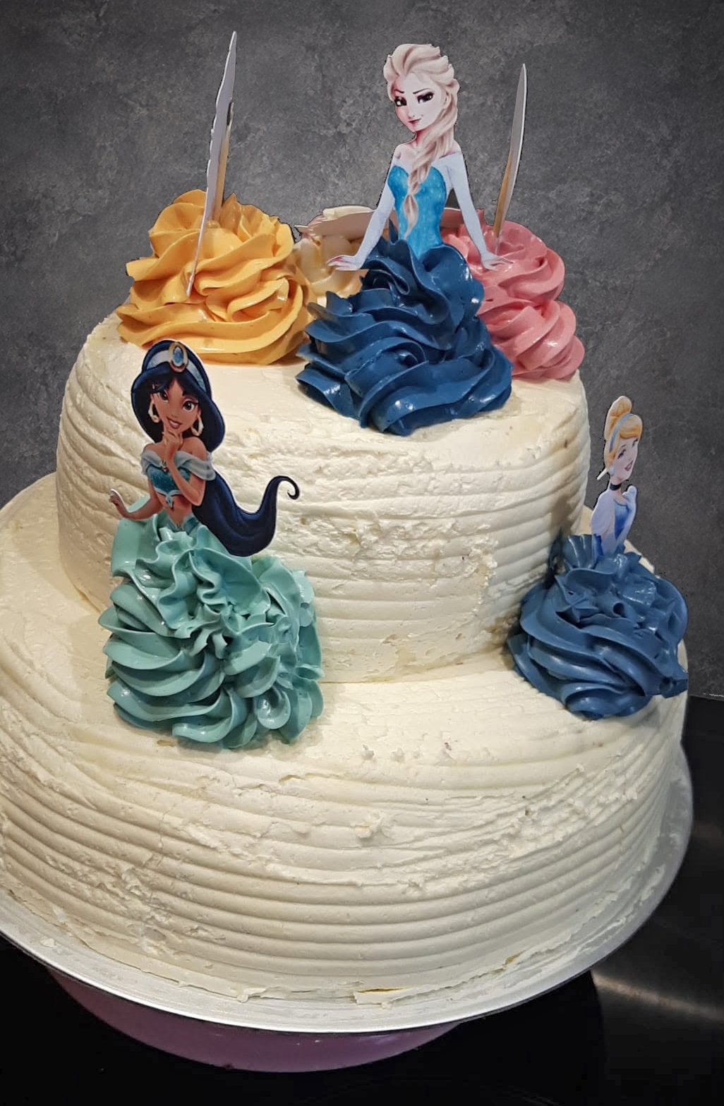 Two-tier buttercream cake decorated with princess figures