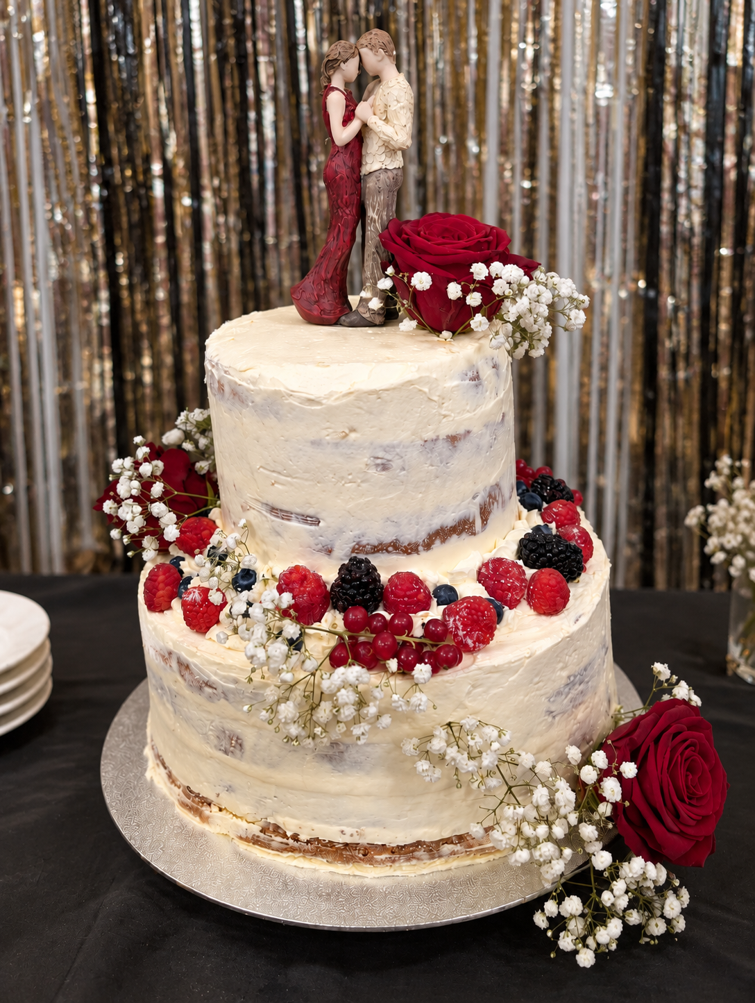 Two-tier naked cake with berries, roses and gypsophila