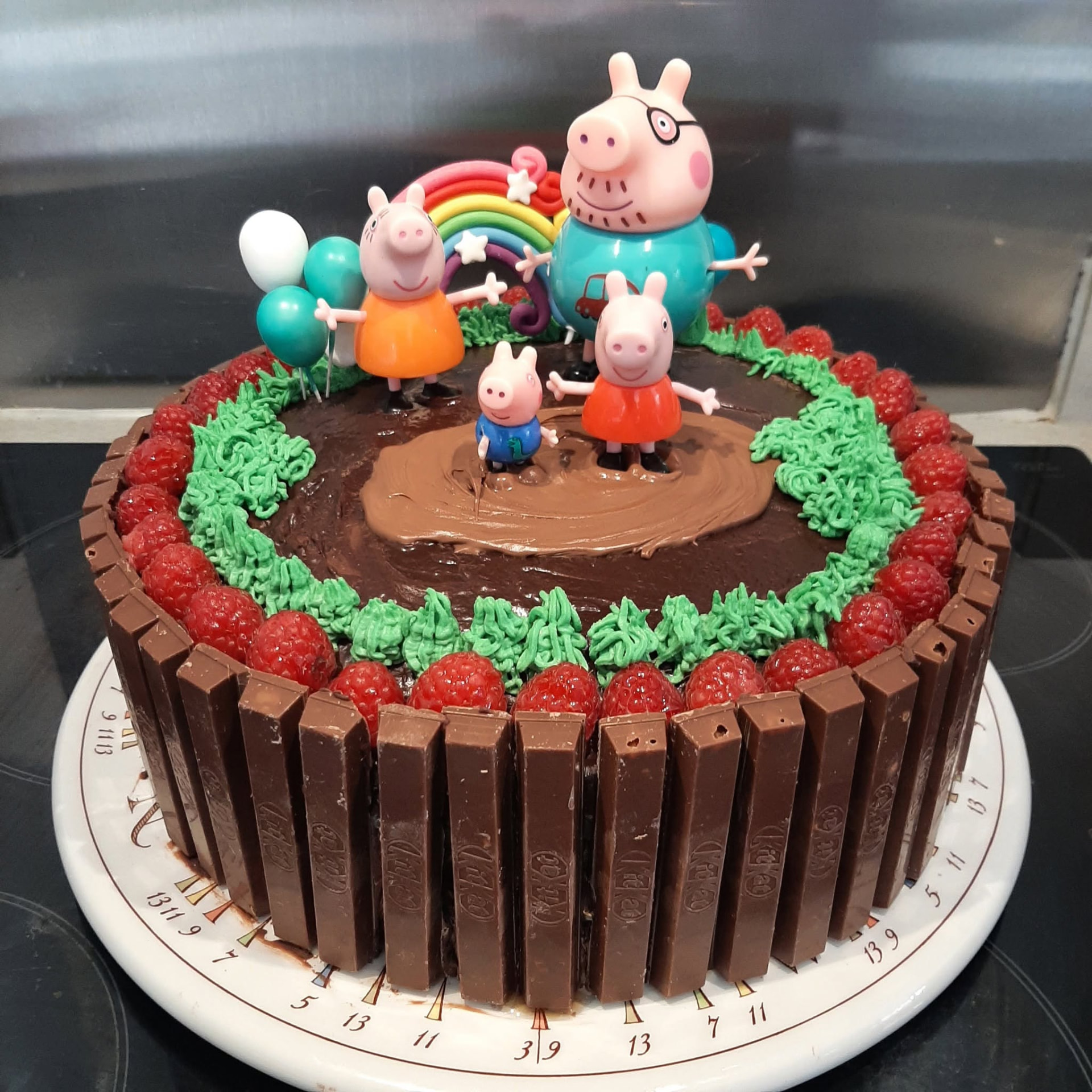 Chocolate birthday cake with raspberries and Peppa Pig figures