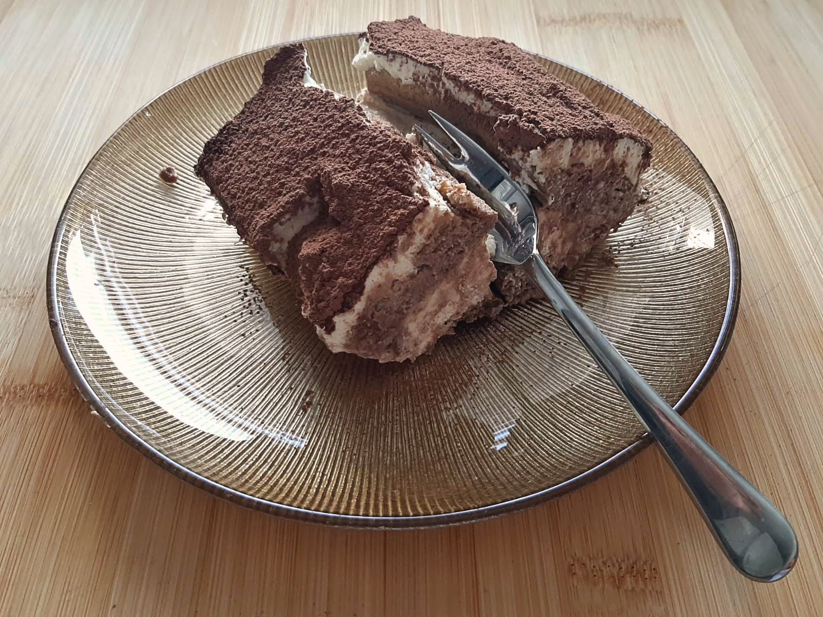 Two slices of tiramisù dusted with cocoa on a glass plate